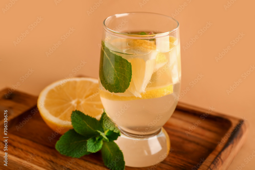 Fototapeta premium Glass of infused water with lemon and mint on brown background