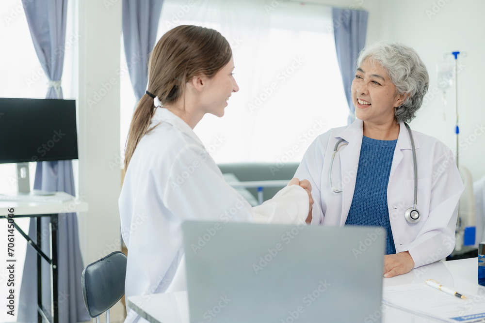 Obraz premium Elderly female doctor joins hands with Dr. Asia, happy to join the team in the medicine room of the pharmaceutical industry hospital, researching the concept of alternative herbal medicine.
