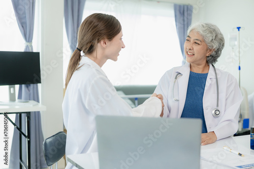 Elderly female doctor joins hands with Dr. Asia  happy to join the team in the medicine room of the pharmaceutical industry hospital  researching the concept of alternative herbal medicine.