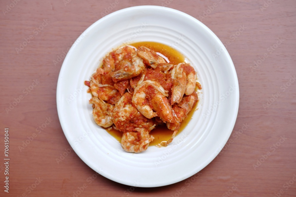 Schezwan Prawns in white plate with wooden background. Schezwan Prawns is indo-chinese cuisine curry dish with prawns or shrimps roasted in Schezwan Sauce. Udang saos Padang Schezwan Prawns in white plate with wooden background. Schezwan Prawns is indo-chinese cuisine curry dish with prawns or shrimps roasted in Schezwan Sauce. Udang saos Padang