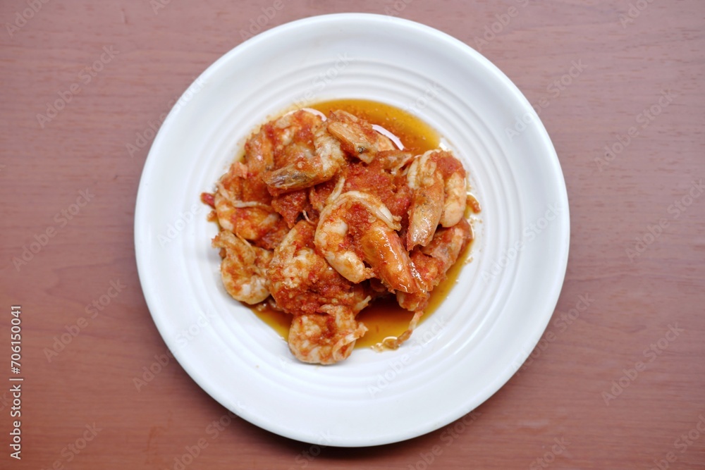 Schezwan Prawns in white plate with wooden background. Schezwan Prawns is indo-chinese cuisine curry dish with prawns or shrimps roasted in Schezwan Sauce. Udang saos Padang 