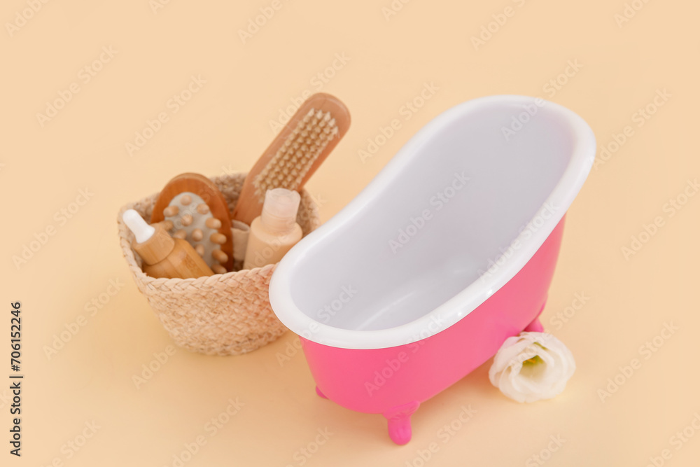 Small bathtub and basket with bath supplies on color background Small bathtub and basket with bath supplies on color background