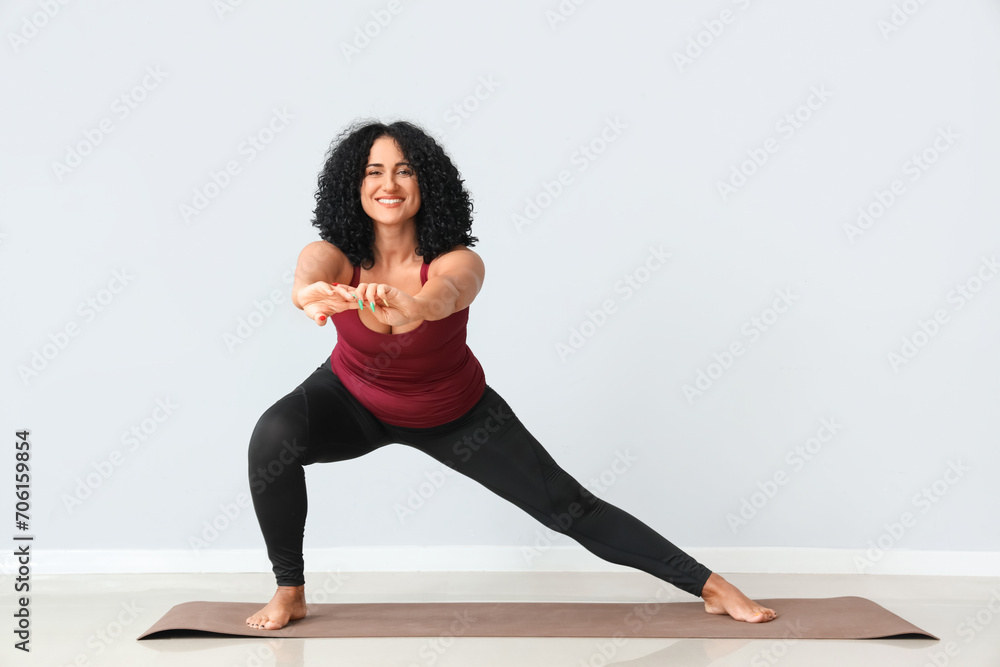 Fototapeta premium Sporty adult woman practicing yoga on grey background