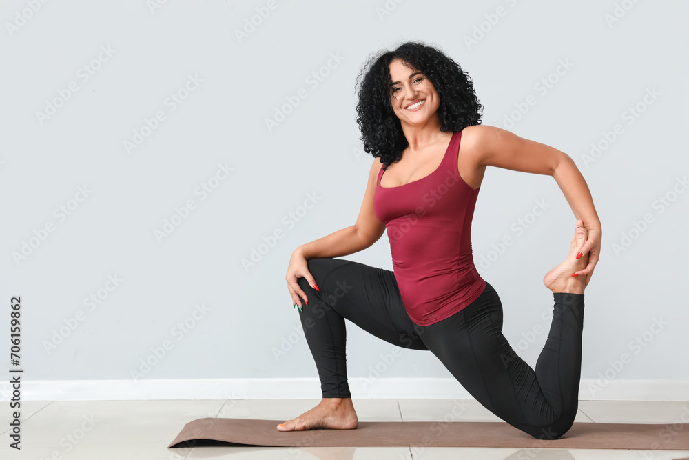 Sporty adult woman practicing yoga on grey background Sporty adult woman practicing yoga on grey background