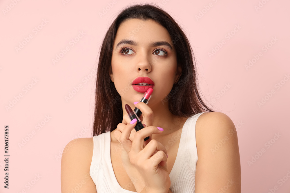 Beautiful young woman with stylish lipsticks on pink background Beautiful young woman with stylish lipsticks on pink background