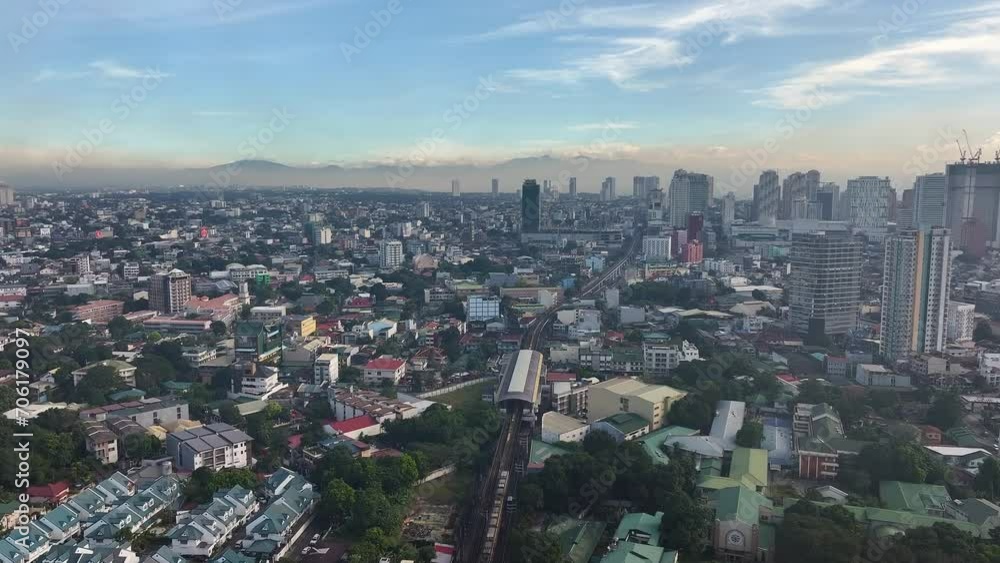 Aerial flight over suburb neighborhood of Manila City with riding train and skyscraper buildings in background at sunset time, Philippines Aerial flight over suburb neighborhood of Manila City with riding train and skyscraper buildings in background at sunset time, Philippines