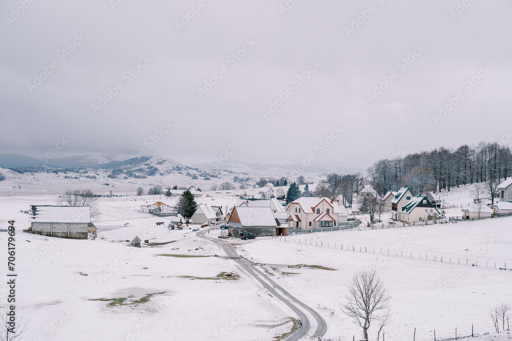 Country road in a small snow-covered village in a mountain valley