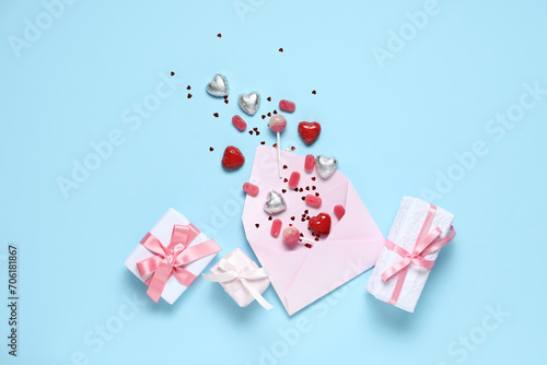 Different tasty sweets with love letter and gift boxes on blue background. Valentine s Day celebration