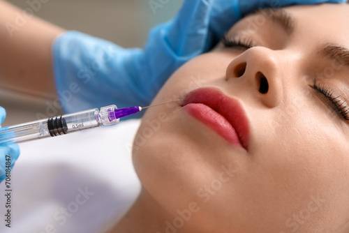 Young woman receiving filler injection in beauty salon, closeup
