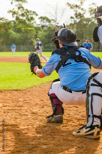 Men playing baseball game. Catcher is getting read to catch baseball during ballgame on a baseball diamond