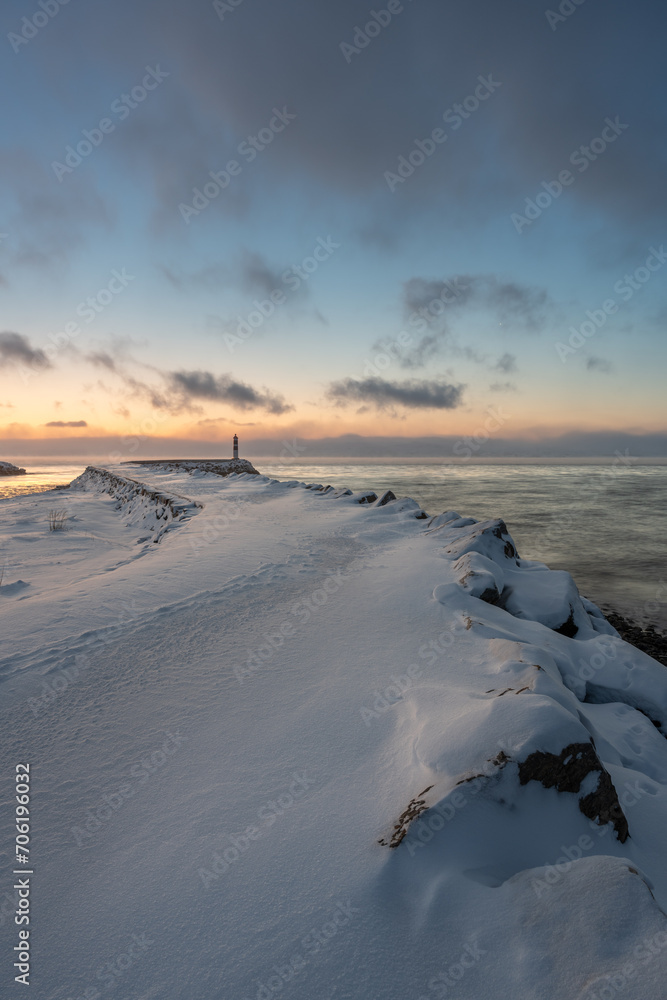 A beacon at the end of a breakwater with beautiful light of the polar night in the background on a cold winter day, Varanger Peninsula, Vestre Jagobselv, Northern Norway