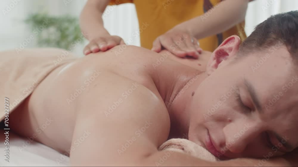 Cropped shot of unrecognizable masseuse giving back massage to male client lying on couch at spa salon Cropped shot of unrecognizable masseuse giving back massage to male client lying on couch at spa salon