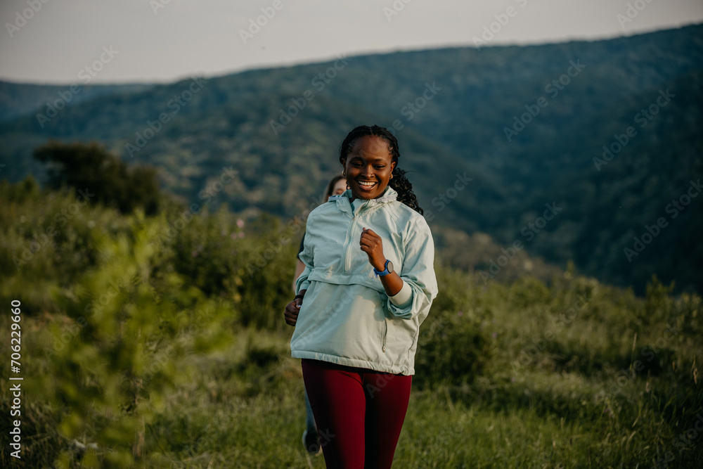 Obraz premium Black and Caucasian women jogging side by side, syncing smartwatches