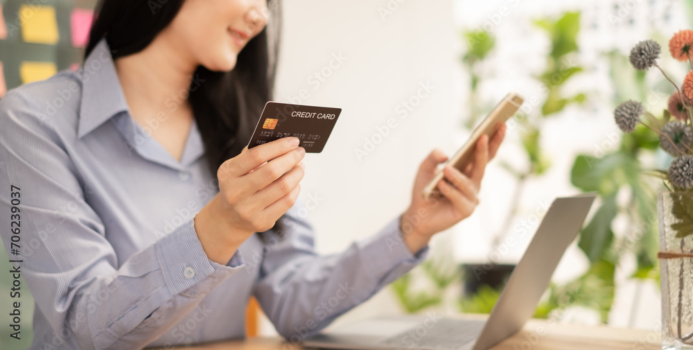 Asian girl shopping online holding credit and using smartphone enter their card number in the mobile phone app to purchase and payment in Internet store Asian girl shopping online holding credit and using smartphone enter their card number in the mobile phone app to purchase and payment in Internet store