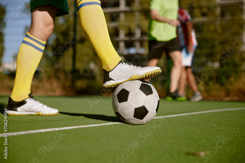 Fototapeta Naklejka Na Ścianę i Meble -  Closeup male foot in boots on soccer ball over green grass field