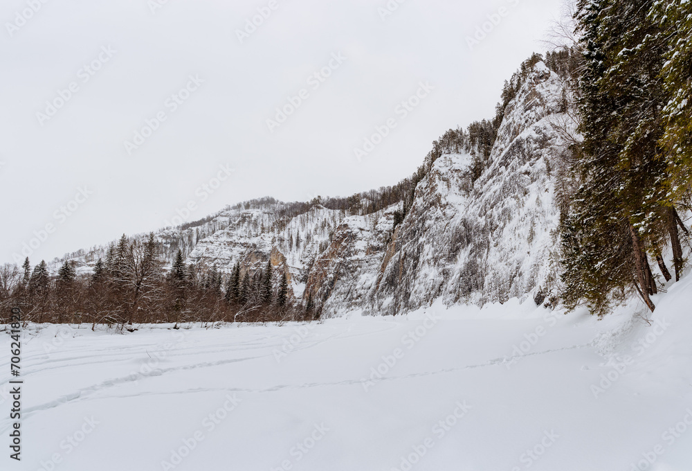 Winter landscape, huge cliffs towering over the river, icy mountain slopes, Tolparov rocks on the Zilim River, Russia Bashkortostan.