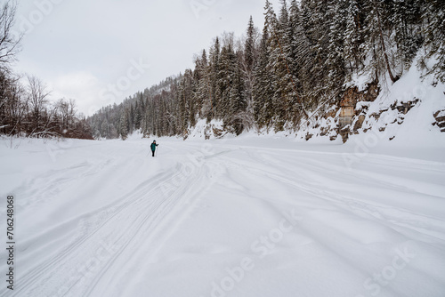 Skiing in nature in winter  a man moves on cross-country skis along the bed of a frozen river  Winter recreation in nature.