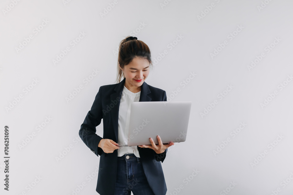Happy asian Thai business woman wear blazer holding laptop, smiling and looking at notebook, typing keyboard isolated over white background wall. Happy asian Thai business woman wear blazer holding laptop, smiling and looking at notebook, typing keyboard isolated over white background wall.