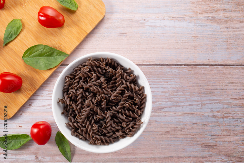 Organic Buckwheat Fusilli pasta,tomatoes cherry,basil leaf,on wooden background.Gluten free noodles.Healthy food concept Organic Buckwheat Fusilli pasta,tomatoes cherry,basil leaf,on wooden background.Gluten free noodles.Healthy food concept