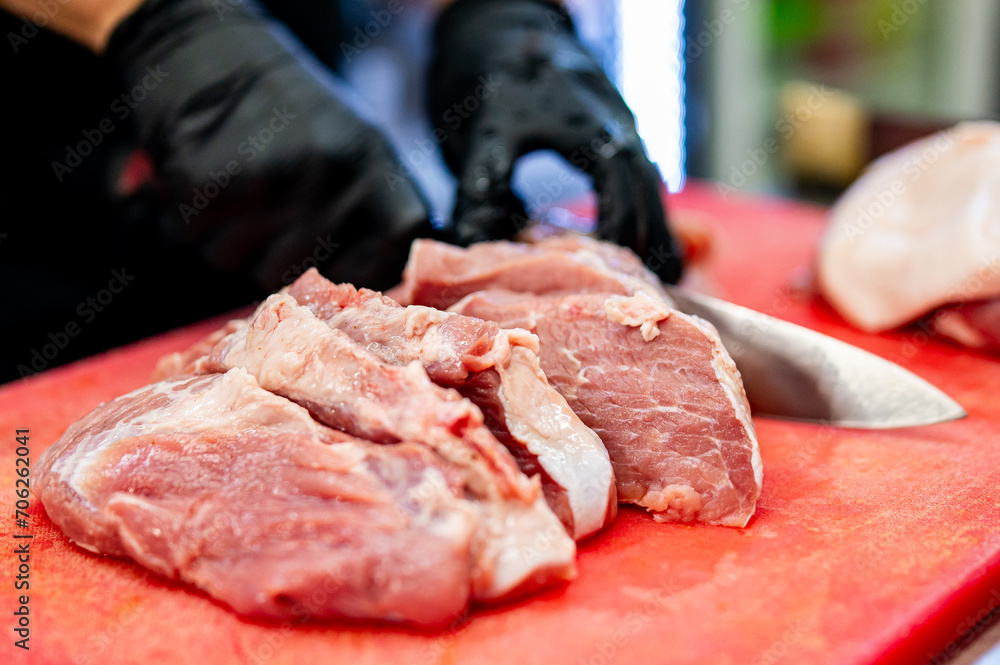 Chef Butcher cutting pork meat with knife on kitchen