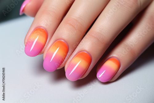 Close up of woman's fingernails with bright pink, orange and yellow ombre colored nail polish design