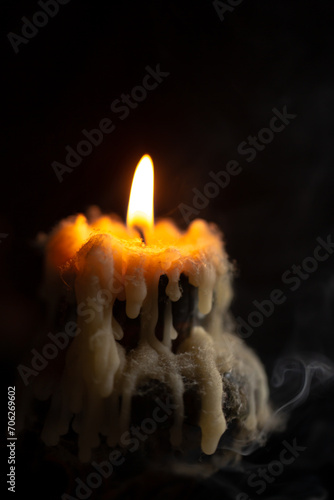 A burning candle in close-up, an antique candlestick covered with wax and cobwebs on a black background photo