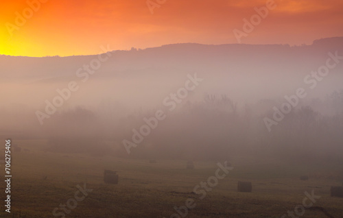 Autumn foggy sunrise. Sunrise photo with a landscape covered in fog, amazing orange sky in the country side.