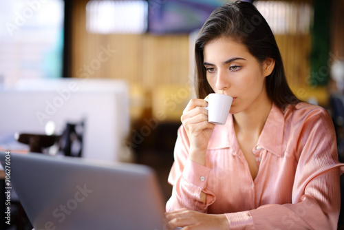 Woman using laptop drinking coffee in a bar interior