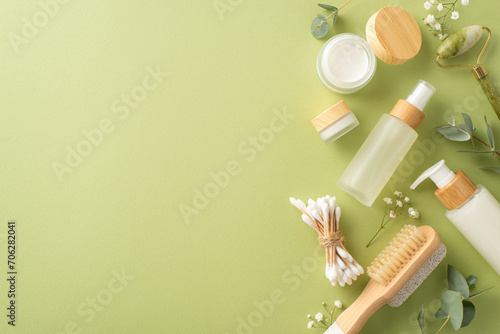 Fototapeta Naklejka Na Ścianę i Meble -  Eco-friendly self-care setup. Top view photo showcasing gua sha tool, lotion, cream bottles, cotton buds, flowers and more on a light green surface. Ideal for promoting a hygienic lifestyle