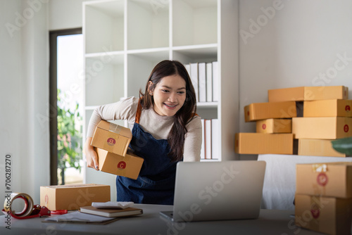Startup SME small business entrepreneur SME or freelance Asian woman using a laptop with box, Young success Asian woman online marketing packag box and delivery concept © Natee Meepian