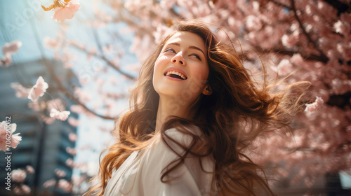 Modern happy young smiling woman with cherry blossoms in the background of a metropolis city.