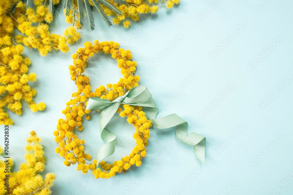 Obraz premium International Women's Day. A banner, a flyer, a beautiful postcard for March 8th. Yellow mimosa flowers in the shape of the number eight and a ribbon bow on a turquoise, blue background.