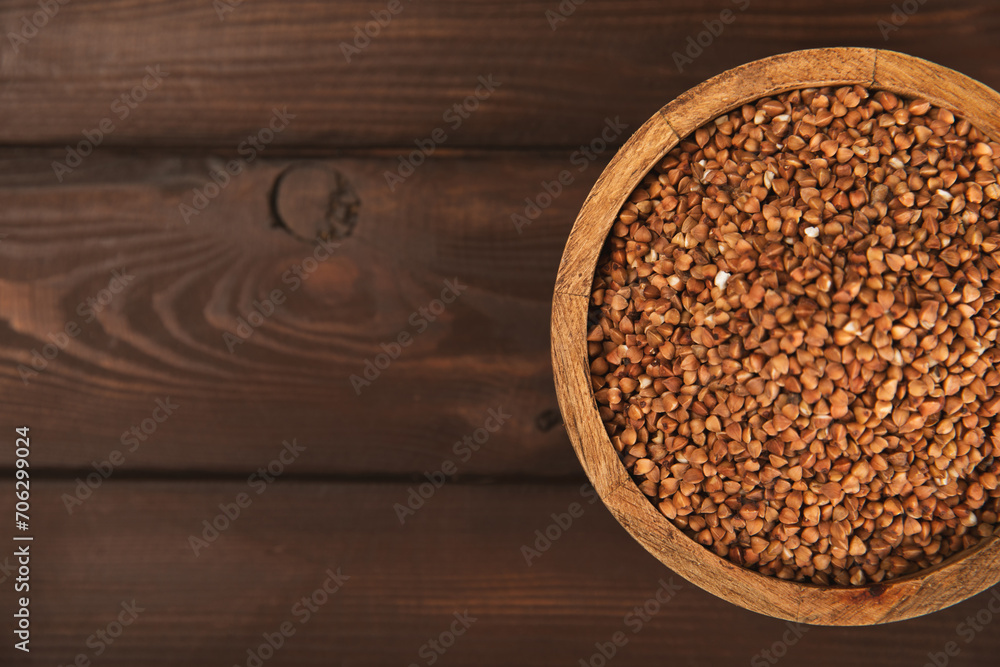 Raw buckwheat in a bowl on a textured wooden background. Wheat grains, porridge, cereals, raw buckwheat in a plate. Healthy food. Porridge. Diet. Organic cerea. Space for text.Copy space. Raw buckwheat in a bowl on a textured wooden background. Wheat grains, porridge, cereals, raw buckwheat in a plate. Healthy food. Porridge. Diet. Organic cerea. Space for text.Copy space.