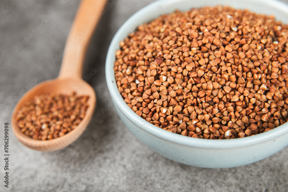 Raw buckwheat in a bowl on a textured wooden background. Wheat grains, porridge, cereals, raw buckwheat in a plate. Healthy food. Porridge. Diet. Organic cerea. Space for text.Copy space. Raw buckwheat in a bowl on a textured wooden background. Wheat grains, porridge, cereals, raw buckwheat in a plate. Healthy food. Porridge. Diet. Organic cerea. Space for text.Copy space.