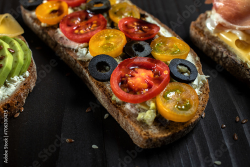 Delicious open sandwich with cherry tomato on a black background.Close up bruschetta