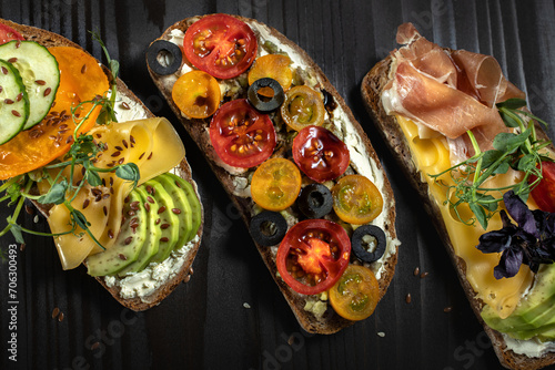 Open sandwiches with avocado, cheese,bacon,cherry tomato and olive.Top view