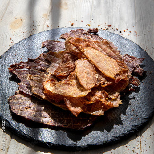 Beef jerky pieces on black plate.Dried meat.Square format