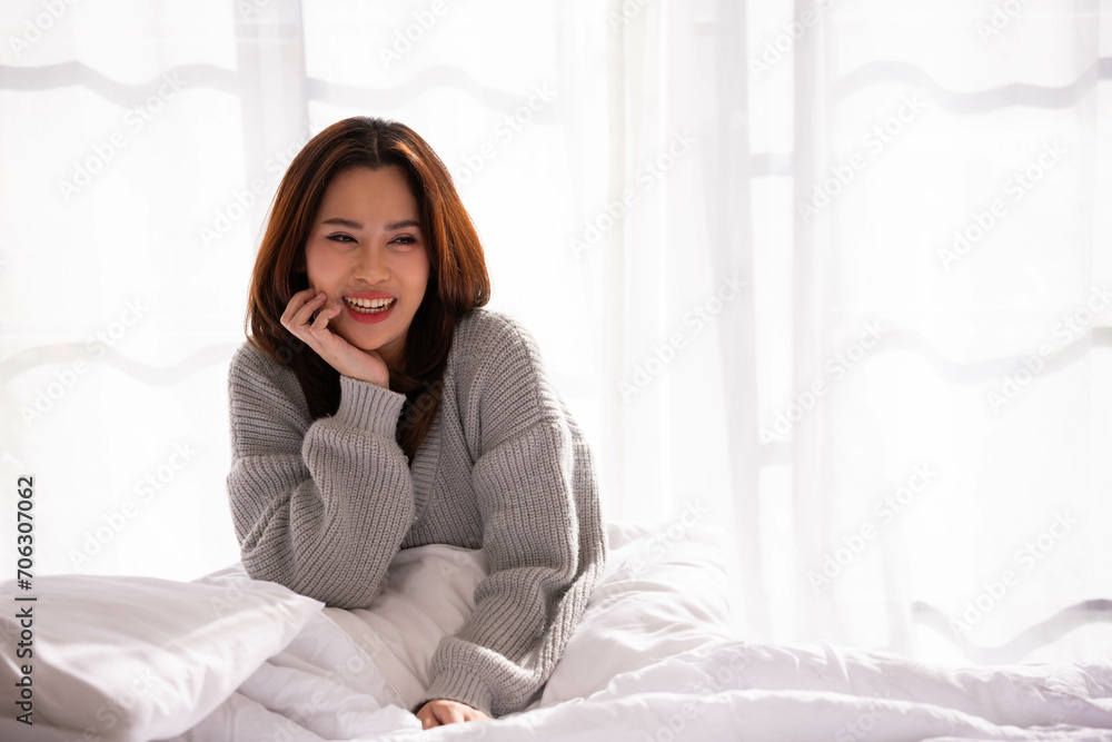 A woman lying at the end of the bed underneath the quilt and smiling, A woman lying at the end of the bed underneath the quilt and smiling,