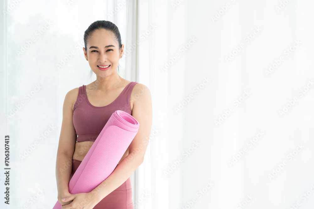 Happy young beautiful asian fitness woman standing pose holding yoga mat. Cheerfully sporty female workout and exercise wearing sportswear. Charming woman relax after fitness training. Happy young beautiful asian fitness woman standing pose holding yoga mat. Cheerfully sporty female workout and exercise wearing sportswear. Charming woman relax after fitness training.