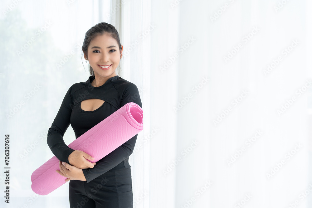 Happy young beautiful asian fitness woman standing pose holding yoga mat. Cheerfully sporty female workout and exercise wearing sportswear. Charming woman relax after fitness training. Happy young beautiful asian fitness woman standing pose holding yoga mat. Cheerfully sporty female workout and exercise wearing sportswear. Charming woman relax after fitness training.