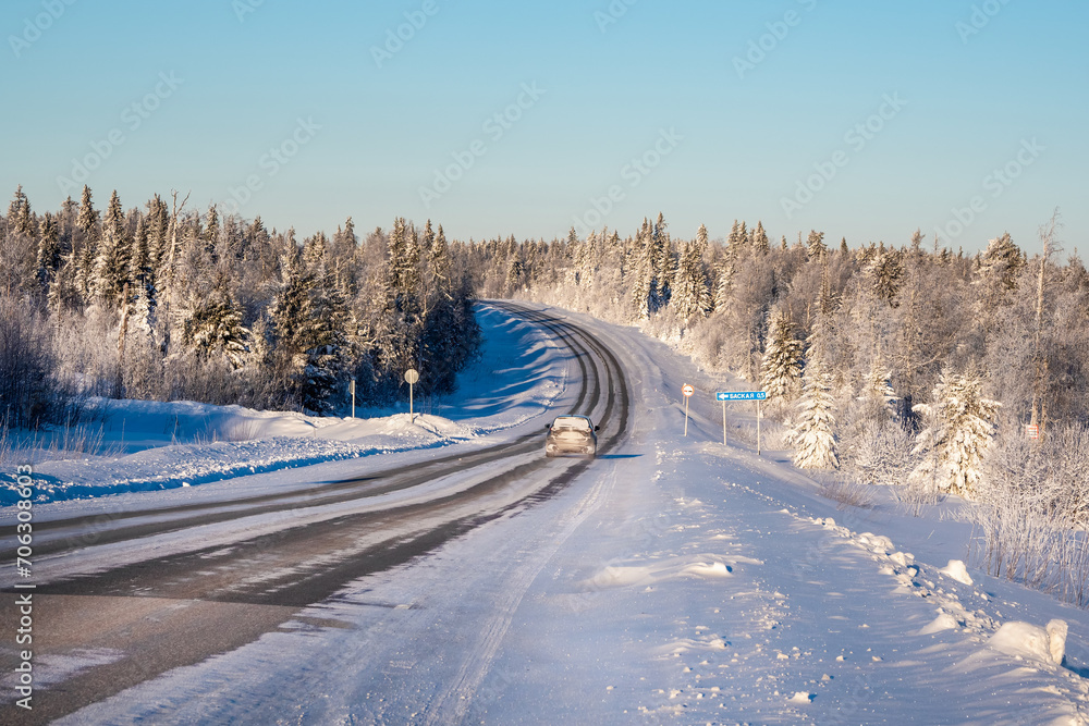 Frosty sunny winter snow-covered highway through hills covered with snowy coniferous forest. Frosty sunny winter snow-covered highway through hills covered with snowy coniferous forest.