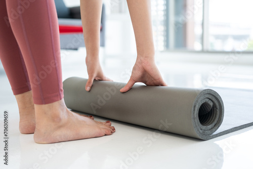 Young beautiful asian woman rolling up exercise mat. Cheerfully sporty female workout and exercise wearing sport wear. Charming woman relax after fitness training class.