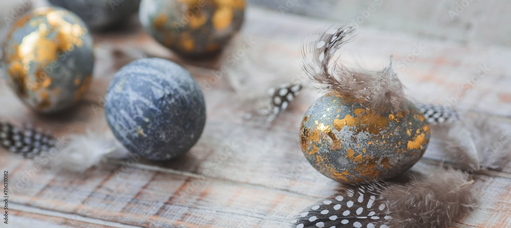 Happy Easter 2024. Stylish grey Easter eggs in the color of marble, concrete, gold and beautiful feathers on a wooden background. Egg coloring with natural dye karkade tea. Happy Easter 2024. Stylish grey Easter eggs in the color of marble, concrete, gold and beautiful feathers on a wooden background. Egg coloring with natural dye karkade tea.