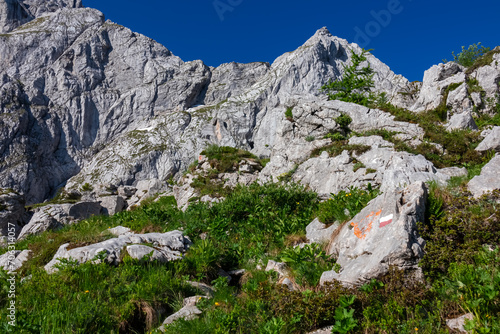 Path mark inidcating hiking trail from Fusine Lake to Mangart saddle in Tarvisio, Julian Alps, Friuli Venezia Giulia, Italy, Europe. Rugged mountain rock formations on extreme alpine terrain in summer photo