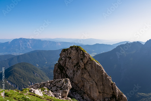 Massive rock formation with aerial view of Gailtal Alps and Karwanks mountains in Carinthia Austria. Seen from hiking trail to Mangart saddle in Julian Alps in Tarvisio, Friuli-Venezia Giulia, Italy