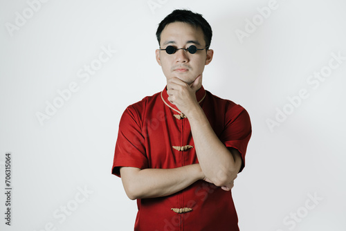 Confused face of Asian man wearing traditional costume on white background. Chinese New Year concept. Gong Xi Fa Cai. photo