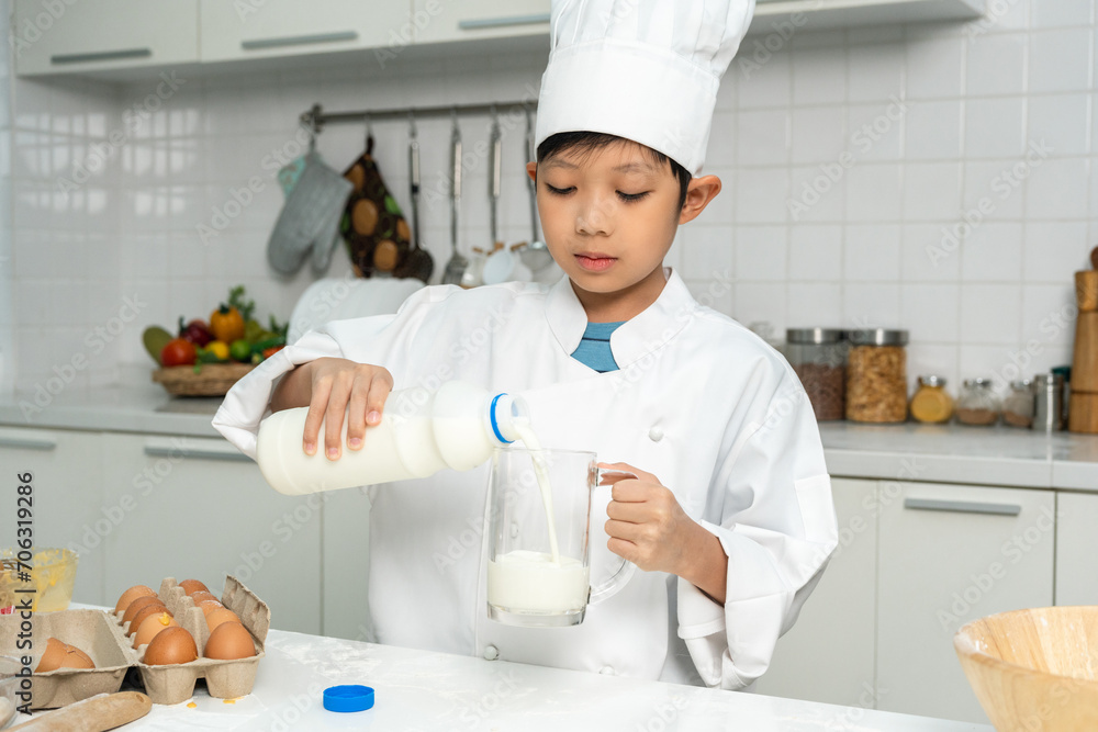 Asian Little chef boy cooking breakfast in the kitchen. Funny kids are preparing food with ingredient. Cute little asian boy a in chef with chef uniform Asian Little chef boy cooking breakfast in the kitchen. Funny kids are preparing food with ingredient. Cute little asian boy a in chef with chef uniform