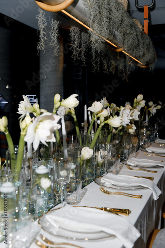 Large table setting plan, luxurious plates and food appliances, flower compositions, side view