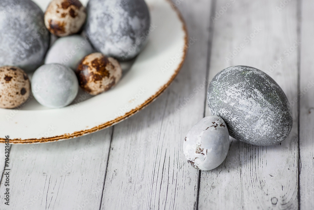 Stylish grey Easter eggs in the color of marble, concrete in a plate and willow branches on a white wooden background. Coloring eggs with natural dye karkade tea. The feast of bright Easter. Stylish grey Easter eggs in the color of marble, concrete in a plate and willow branches on a white wooden background. Coloring eggs with natural dye karkade tea. The feast of bright Easter.