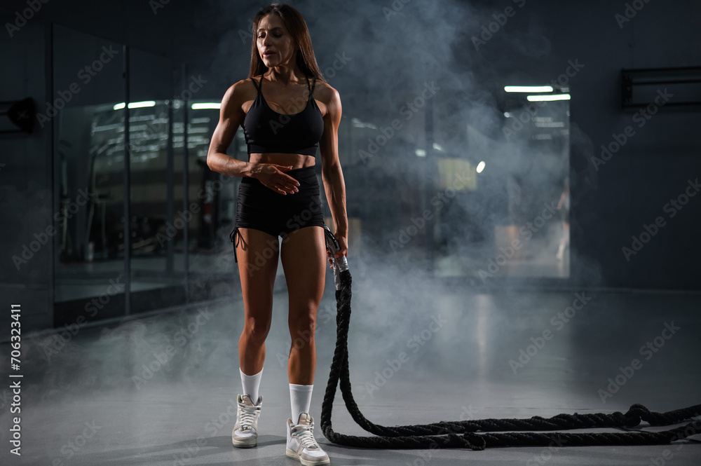 Caucasian woman doing exercise with ropes. Circuit training in the gym.